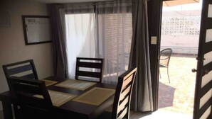 A dining area with a table and chairs, a window with curtains, and an open door leading outside. - My Depa Vanilla. In the heart of Cd. Valleys. (Ciudad Valles)