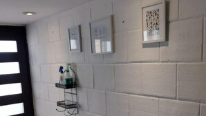 A hallway with a white brick wall, recessed ceiling lights, and a black-framed door. - My Depa Vanilla. In the heart of Cd. Valleys. (Ciudad Valles)
