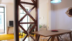 Uma sala de jantar com uma mesa e cadeiras de madeira, um tapete amarelo e uma grande estrutura de vigas de madeira.