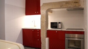 Uma cozinha compacta com armários vermelhos, um micro-ondas e um forno.