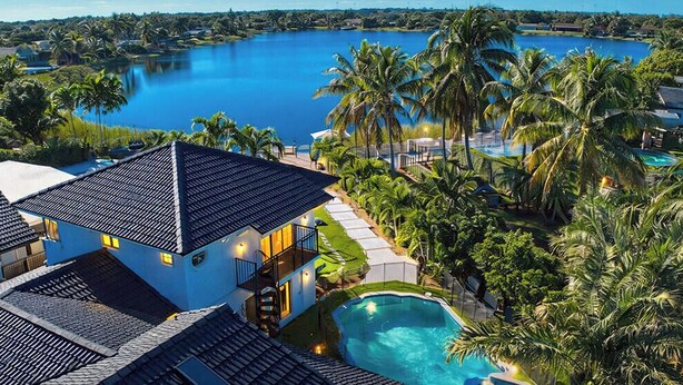 Un resort con una grande piscina, una dependance e vista su un lago.