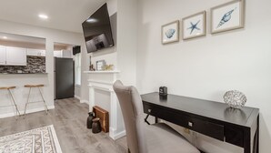 A modern living room with a black TV, a fireplace, and a dining area with stools. - One bedroom apartment in downtown Canandaigua (Canandaigua)