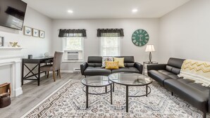 A modern living room with a sofa, two coffee tables, a fireplace, and a large wall clock. - One bedroom apartment in downtown Canandaigua (Canandaigua)
