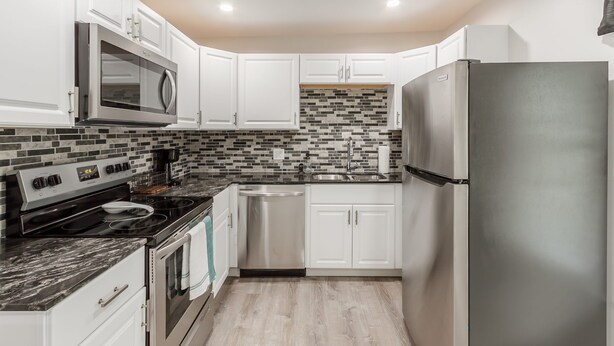A modern kitchen with white cabinets, a stainless steel refrigerator, a microwave, and a dishwasher. - One bedroom apartment in downtown Canandaigua (Canandaigua)