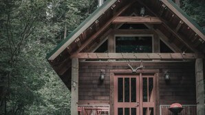 Una cabaña rústica con fachada de madera, un porche delantero y una chimenea.