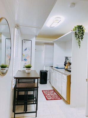 Enjoy meals in this cozy kitchen with a dining table and chairs, a potted plant, and a convenient trash bin.