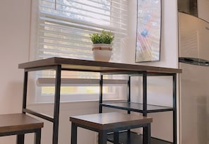 Enjoy cooking in this kitchen with a dark table, stainless steel appliances, and a green plant above.