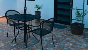 An outdoor patio with a table and chairs, a green umbrella, and potted plants. - My Depa Cinnamon In the Center of Cd. valleys (Ciudad Valles)