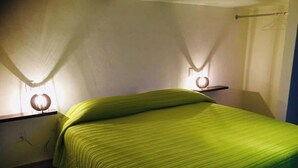 A small, neatly made bed with a green bedspread in a room with white walls and a wooden floor. - My Depa Cinnamon In the Center of Cd. valleys (Ciudad Valles)
