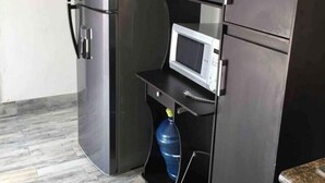 A compact kitchen with a refrigerator, microwave, and a water dispenser. - My Depa Cinnamon In the Center of Cd. valleys (Ciudad Valles)