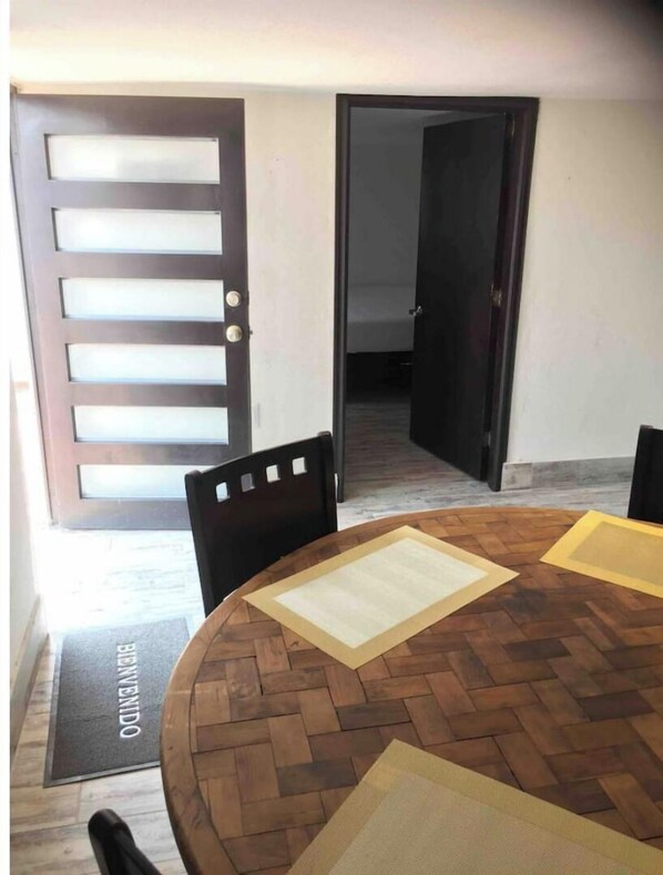 Een eethoek met een ronde houten tafel, stoelen en een deurmat met de tekst 'BILLINDO'.