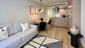 A modern living room with a sofa, a dining table, and chairs. There is a kitchen area with a stove and cabinets. - 11 Reyes Catolicos Premium Homes - Deluxe Homes (Alicante (Alacant))