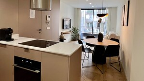 A modern kitchen with a built-in stove, a large island with a sink, and a dining area with a round table and chairs. - 11 Reyes Catolicos Premium Homes - Deluxe Homes (Alicante (Alacant))