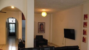 A living room with a sofa set, a television mounted on the wall, and a framed picture on the wall. - My Depa Waterfall In the Center of Cd. valleys (Ciudad Valles)