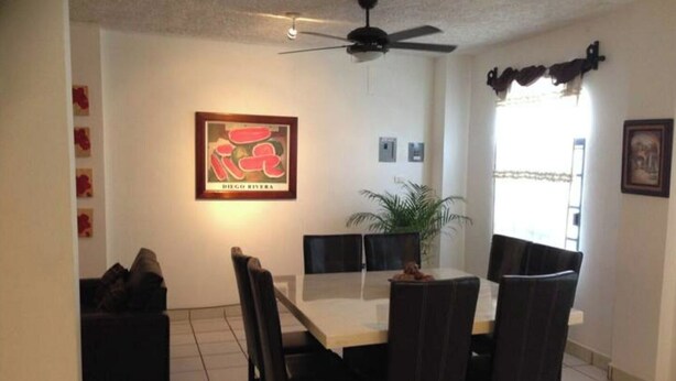 A dining area with a table and chairs, a ceiling fan, and a framed artwork on the wall. - My Depa Waterfall In the Center of Cd. valleys (Ciudad Valles)