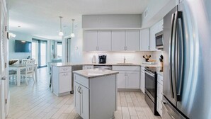 A modern kitchen with white cabinets, a stainless steel refrigerator, and a central island.