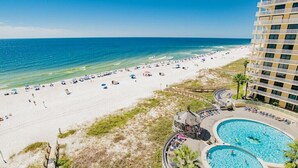 A beach resort with a large pool area, a beach, and a high-rise building.