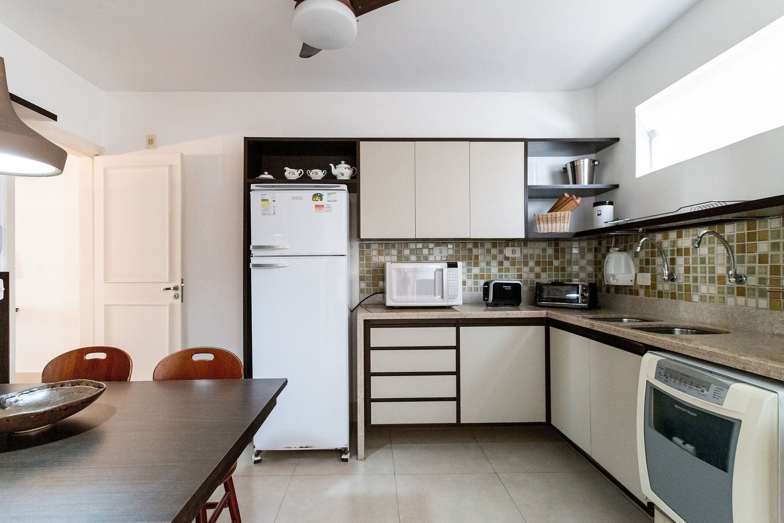 Una cocina compacta equipada con refrigerador, microondas, tostadora, fregadero y lavavajillas.