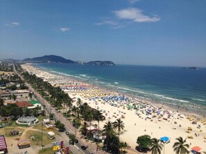 A beach with numerous umbrellas and people. - Apartamento Enseada - Guarujá (Guarujá)