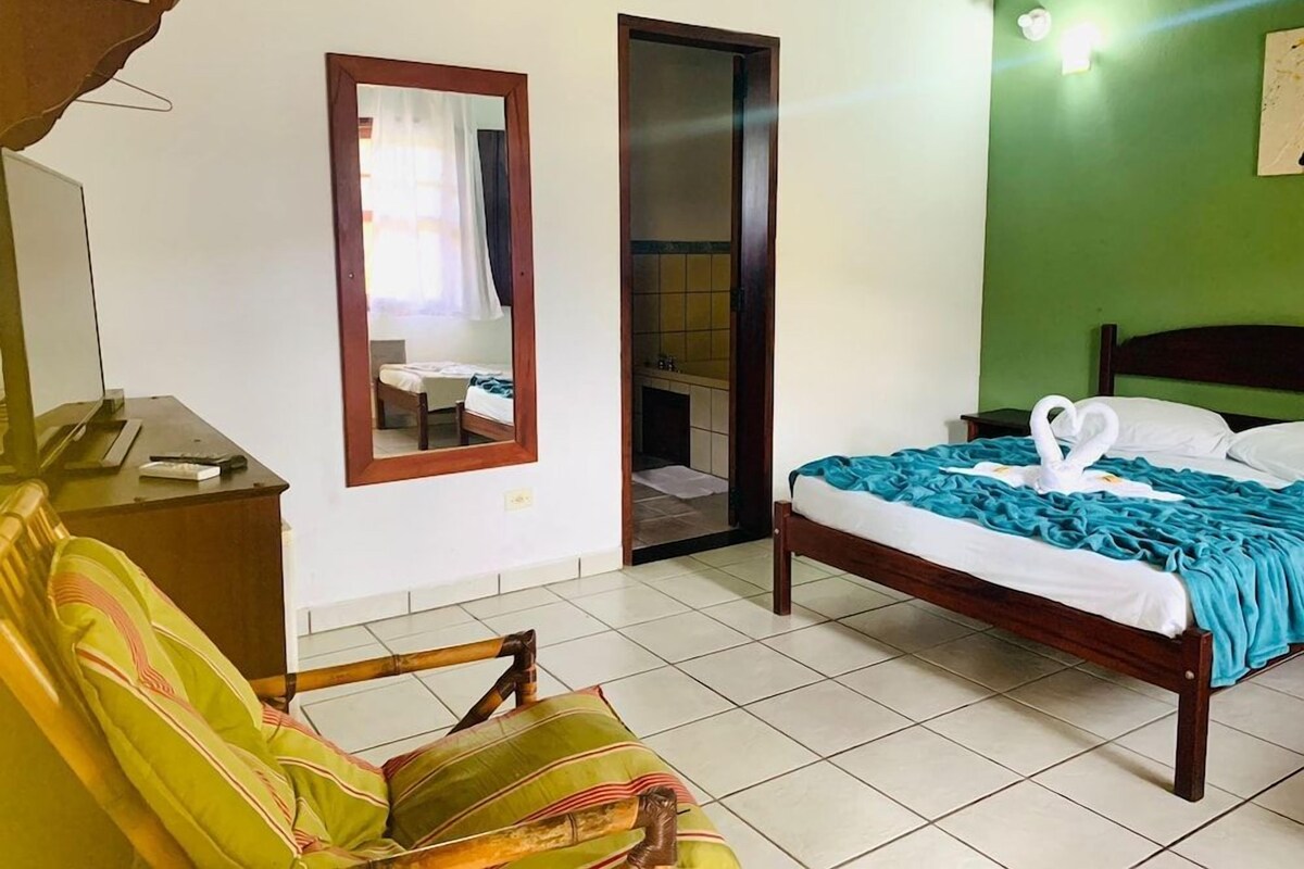 A hotel room with a bed, a chair, a desk, and a mirror.