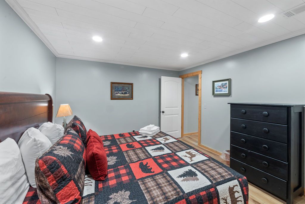 Une chambre à coucher avec un lit, des oreillers, une couette, une commode et une porte.