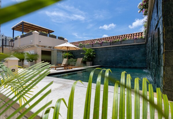 A pool area with a pergola, lounge chairs, and a stone wall. - CC2-3 HABITACION DOBLE EN GETSEMANI (Cartagena)