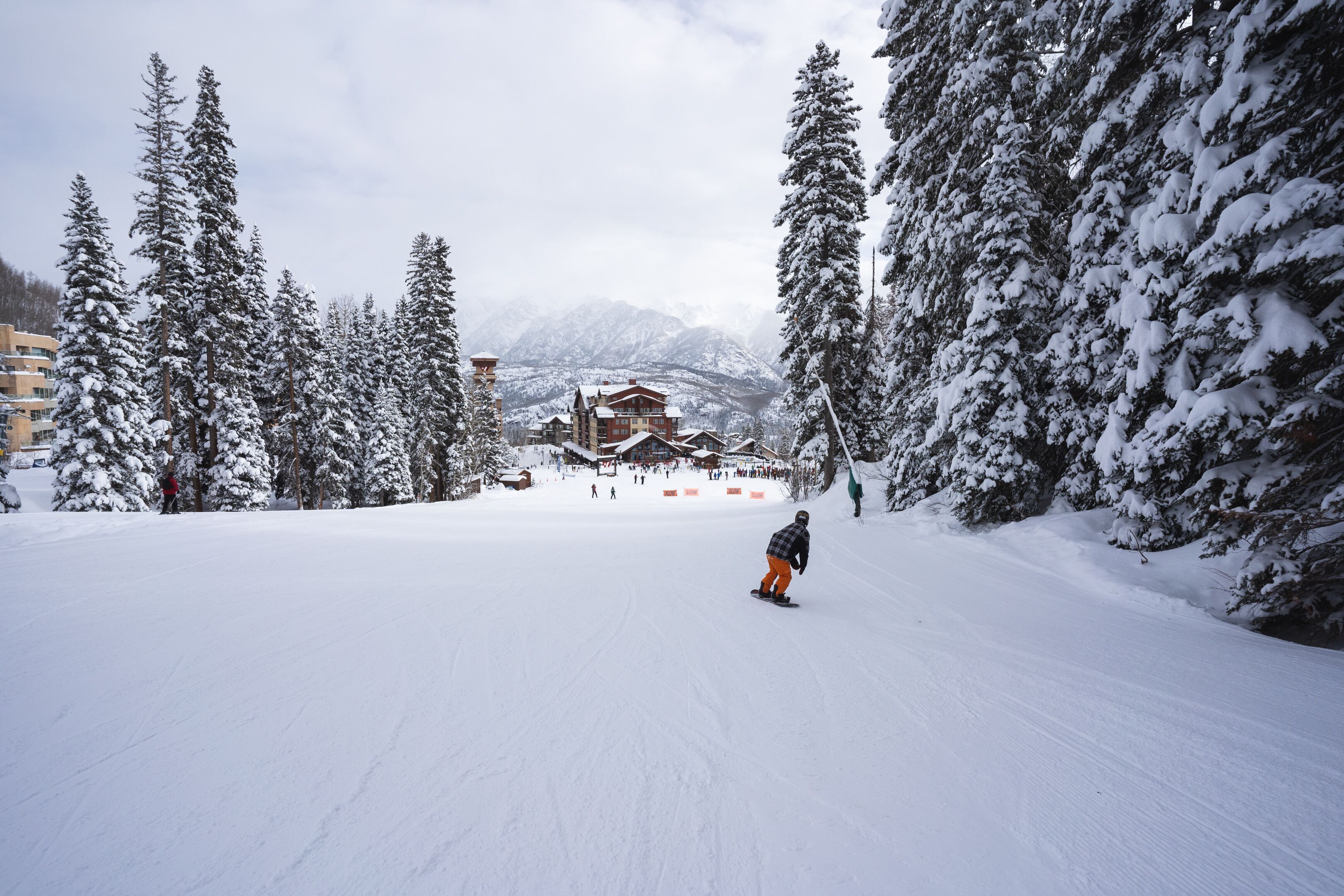 A snow-covered ski slope with a lodge in the background.