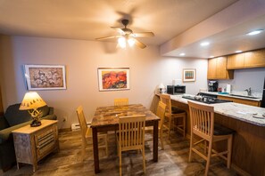 A compact kitchen with wooden cabinets, a dining table, chairs, a ceiling fan, and artwork on the walls. - 1BR Cascade Village condo with pool, hot tub, fireplace, and full kitchen. (Durango)