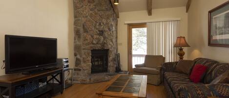 A living room with a stone fireplace, a television, a sofa, and a lamp.