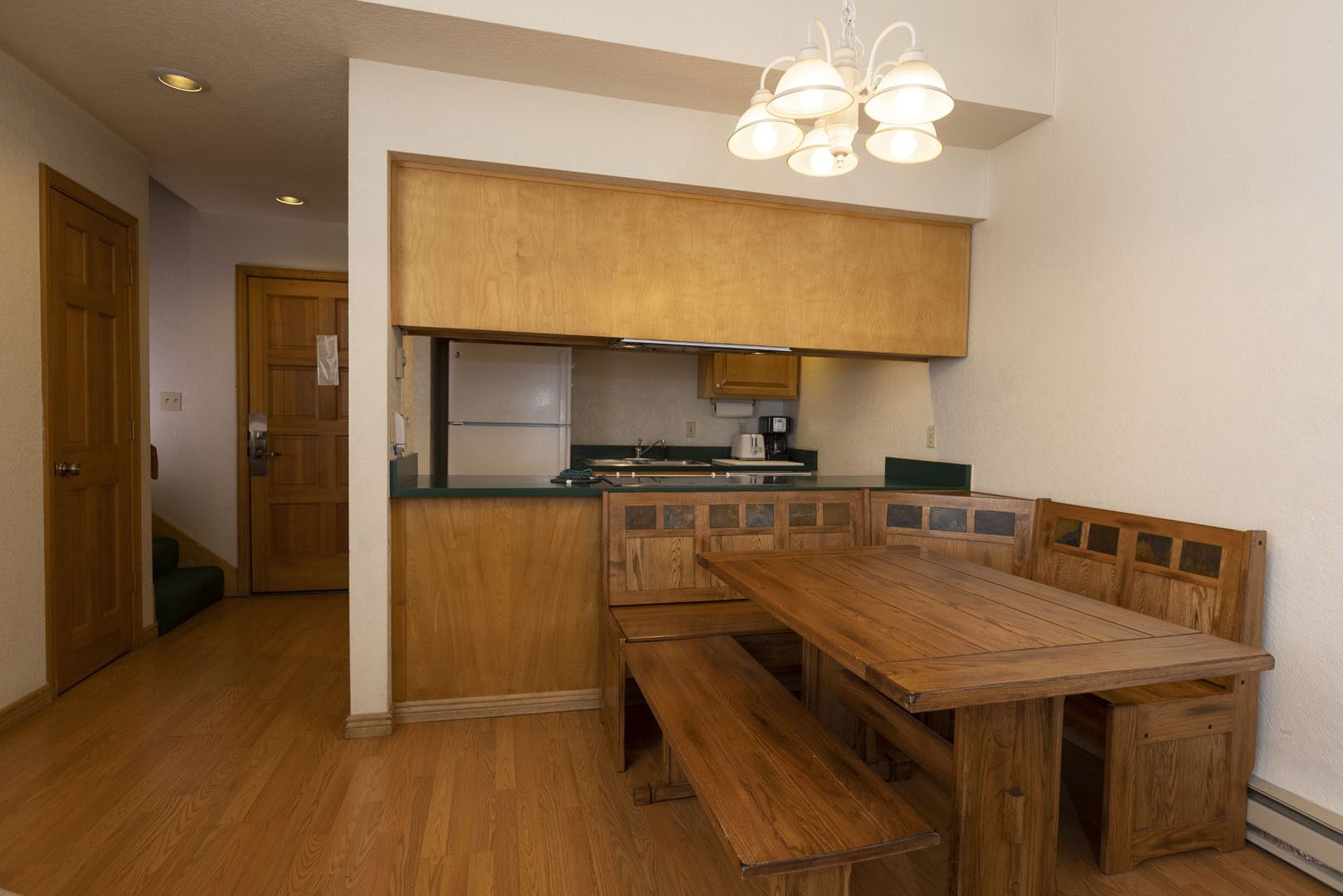 A compact kitchen with wooden cabinets, a built-in bench seating, and a central island.