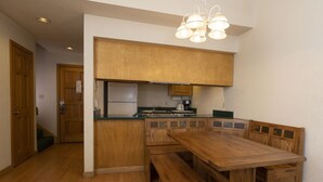 A compact kitchen with wooden cabinets, a built-in bench seating, and a central island. - Cascade Village 318 - Pool and Hot Tub Access (Durango)