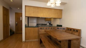 A compact kitchen with wooden cabinets, a built-in bench seating, and a central island.