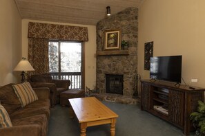 Una sala de estar acogedora con chimenea de piedra, televisor y un sofá cómodo.