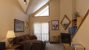 A living room with a sofa, a coffee table, a lamp, a fireplace, a mirror, and a window with blinds. - Cascade Village 357: One Bedroom mountain-view condo with pool, hot tub & balcony. (Durango)