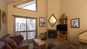 A living room with a fireplace, a large window, and a balcony. - Cascade Village 357: One Bedroom mountain-view condo with pool, hot tub & balcony. (Durango)