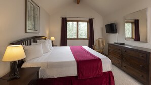 A bedroom with a bed, bedside lamps, a dresser, a television, and a window with curtains. - Two Bedroom - Cascade Village condo with mountain views, pool, hot tub, and ski access (Durango)