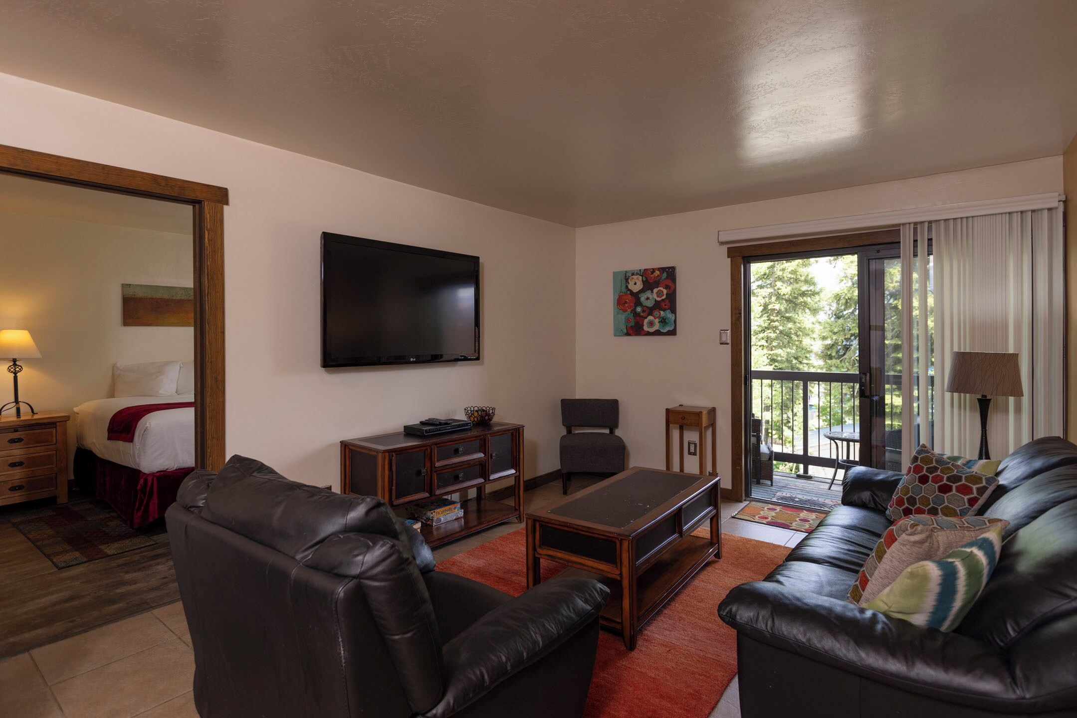 Una sala de estar con sofá, mesa de centro, televisor y ventana con cortinas.