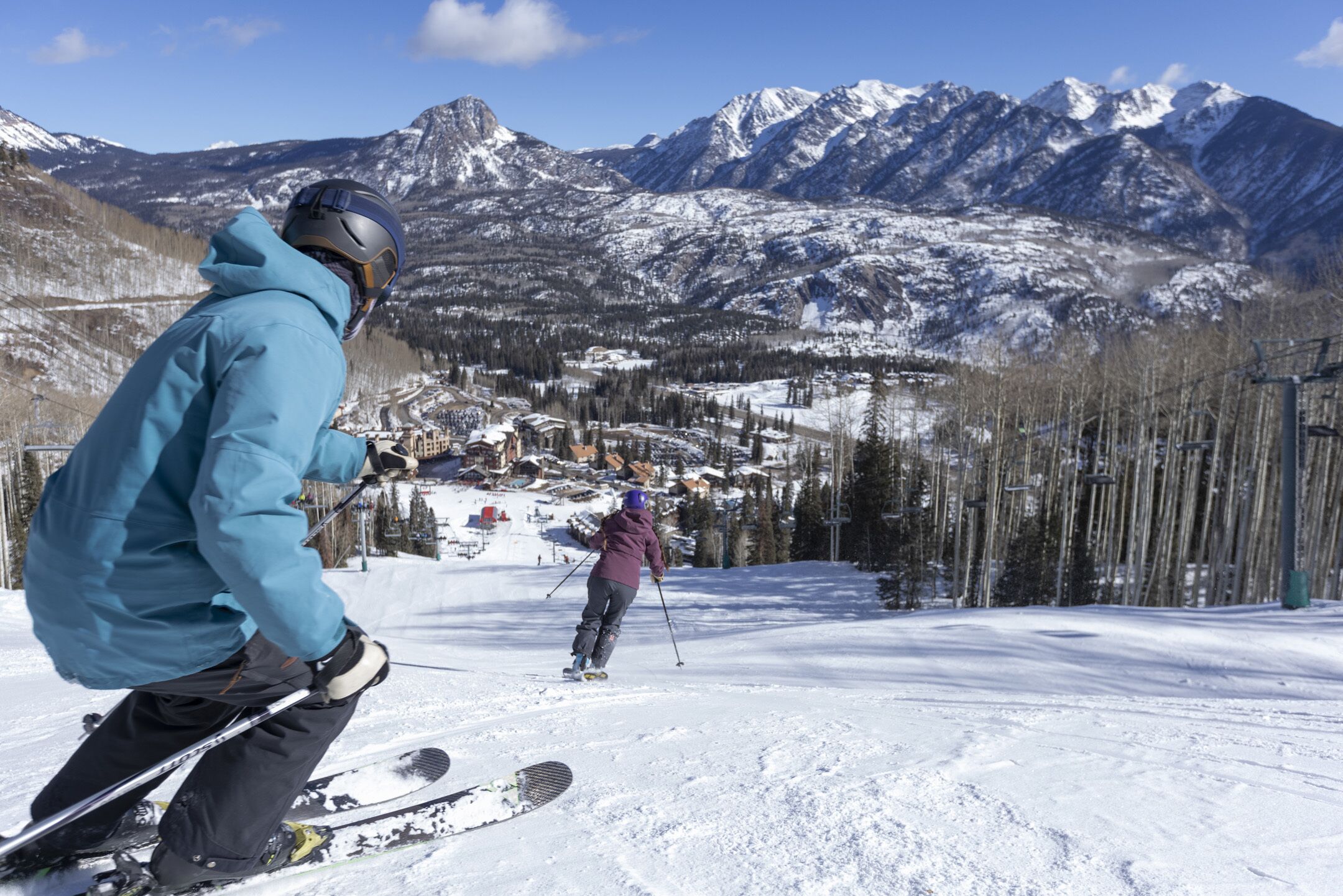 A person skiing on a snowy slope with a mountain backdrop.