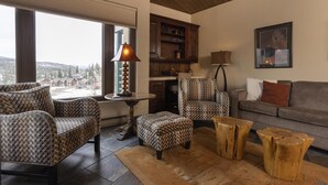 A cozy living room with patterned furniture, a view of a snowy landscape, and a fireplace.