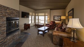 A living room with a stone fireplace, a television mounted on the wall, a sofa, a chair, and a lamp. - Eolus 525 - Managed by Purgatory Result (Durango)