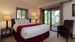 A hotel room with a large bed, two bedside lamps, a chair, and a view through a sliding glass door. - Purgatory Resort Retreat with pool, hot tub, and balcony - Three Bedroom (Durango)