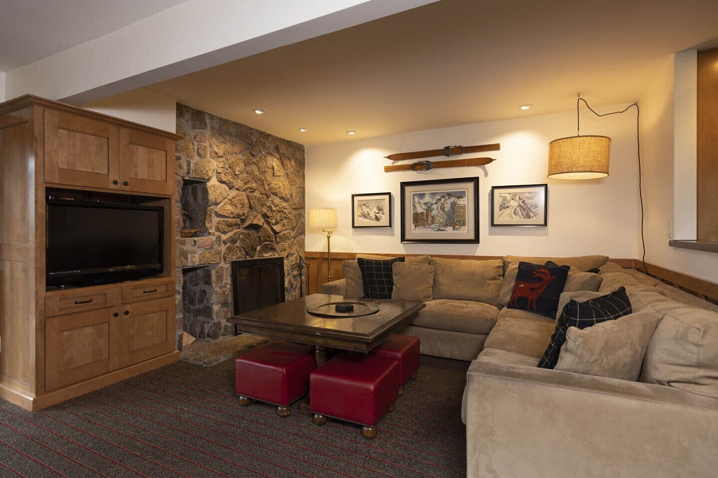 A cozy living room with a stone fireplace, a flat-screen TV, a sofa, and a coffee table.