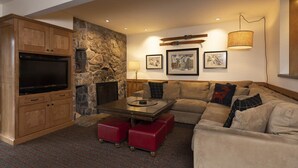 A cozy living room with a stone fireplace, a flat-screen TV, a sofa, and a coffee table. - Purgatory Resort Retreat with pool, hot tub, and balcony - Three Bedroom (Durango)