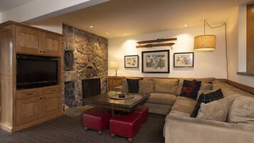 A cozy living room with a stone fireplace, a flat-screen TV, a sofa, and a coffee table.