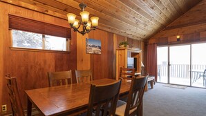 Une salle à manger en bois, avec un lustre, des chaises en bois et une grande table.