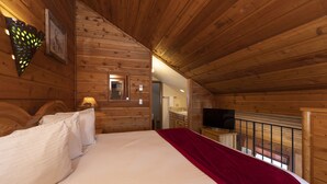 Une chambre dans une cabane en bois, équipée d’un lit, d’une télévision et d’un miroir.
