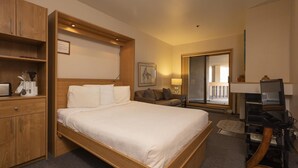 A hotel room with a large bed, wooden wardrobe, a desk with a computer, and a view of the outside balcony. - Cozy Studio for 2 at Purgatory Village - Kendall 230 (Durango)