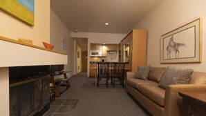 A living room with a sofa, TV, fireplace, and a dining area with chairs and a table. - Cozy Studio for 2 at Purgatory Village - Kendall 230 (Durango)