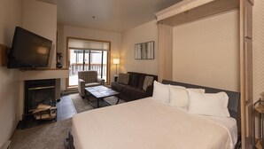 A hotel room with a large bed, a TV, a fireplace, a sofa, and a view of the outdoors. - Cozy Studio for 2 at Purgatory - Kendall 232 (Durango)