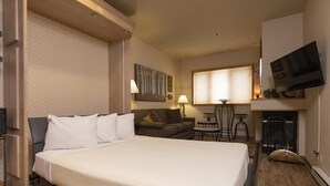 Una habitación de hotel con una cama grande, un sofá, un televisor y una pequeña mesa.